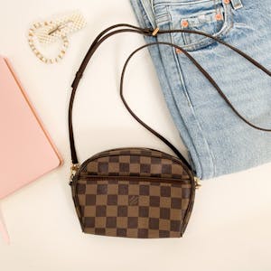 Chic setup of a designer handbag paired with denim and accessories, promoting luxury fashion.